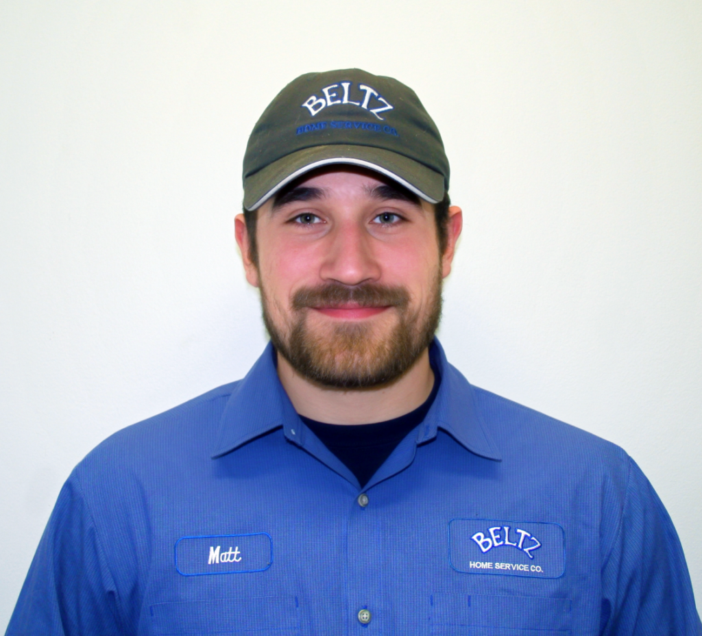 Meet The Team | Beltz Home Service Co. A Man In A Blue Uniform And Cap With The &Quot;Beltz&Quot; Logo, Wearing A Name Tag That Reads &Quot;Matt,&Quot; Smiles At The Camera Against A White Background, Embodying The Spirit Of His Dedicated Team.