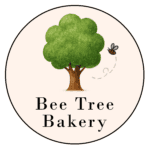 A Green Tree With A Bee Flying Near It, Above The Text “Bee Tree Bakery” In Black Letters, All Within A Circular Border.